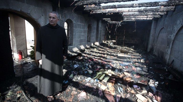 A priest inspects damage caused to the Church of the Multiplication of the Loaves and Fishes in Galilee, Israel, by an arson attack (18 June 2015)