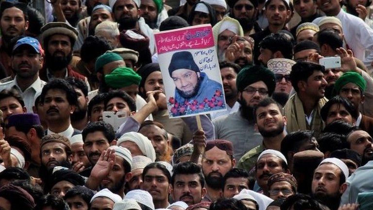 People hold the photo of police officer Mumtaz Qadri, the convicted killer of a former governor, during his funeral, in Rawalpindi, Pakistan, Tuesday, March 1, 2016.