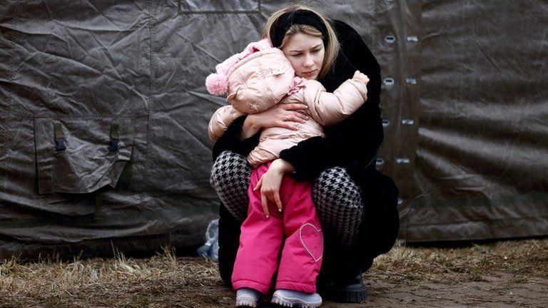 A woman fleeing Russian invasion of Ukraine hugs a child at a temporary camp in Przemysl, Poland