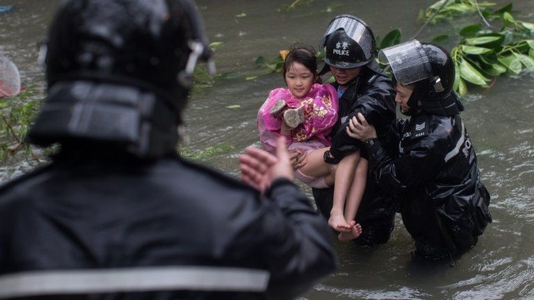 Police officers rescue a child from a flooded street in Hong Kong