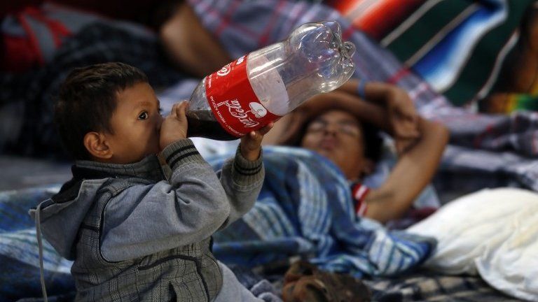 A child drinks from a Coca-Cola bottle in Puebla