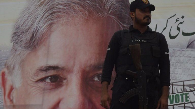 A Pakistani policeman stands guard beside an election poster featuring an image of Shahbaz Sharif, the younger brother of ousted Pakistani prime minister Nawaz Sharif and the head of Pakistan Muslim League -Nawaz (PML-N), Karachi 25 June 2018