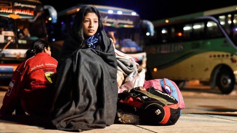 A Venezuelan girl sits next to her belongings at the border between Ecuador and Peru