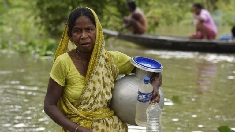 An Indian woman collects drinking water in flood affected Kamrup district of Assam, India, 14 July 2020.
