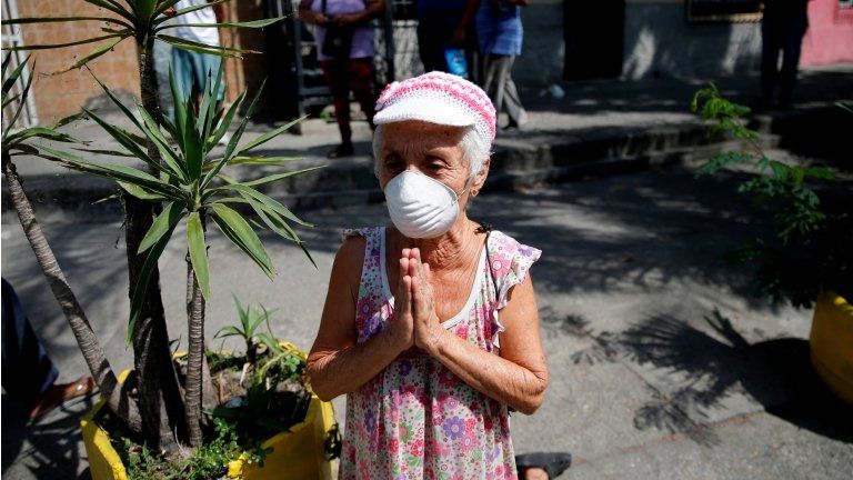 A woman on her knees while wearing a protective mask reacts as The Nazarene of St Paul procession passed-by despite a nationwide quarantine due to the coronavirus disease (COVID-19) outbreak in Caracas, Venezuela April 8, 2020.