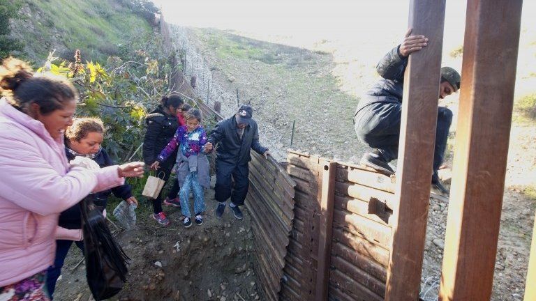 Honduran migrants climb over the U.S.-Mexico border fence