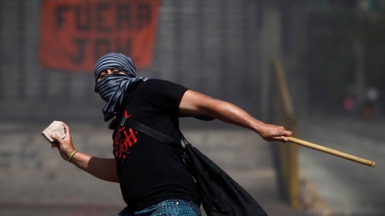 A demonstrator throws a rock towards police during a protest against Honduras" President Juan Orlando Hernandez and his government in Tegucigalpa, Honduras, January 27, 2019.