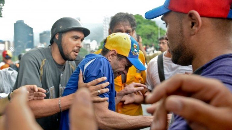 Opposition leader Henrique Capriles reacts to tear gas