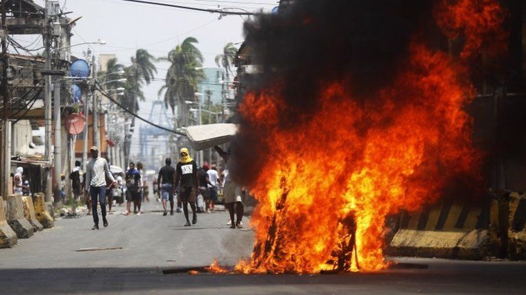 Protesters walk next to a fire in a street of Colon, Panama on March 13, 2018, during a general strike.