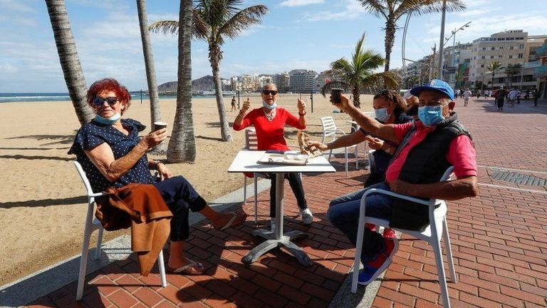Italian tourists celebrate being able to sit on a terrace at promenade of Las Canteras beach