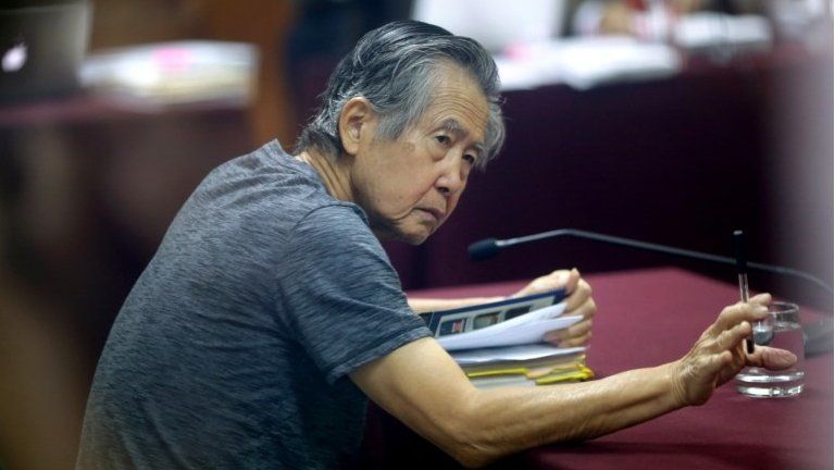 In this April 23, 2014 file photo, jailed former Peruvian President Alberto Fujimori, photographed through a glass window, attends his trial at a police base on the outskirts of Lima, Peru.