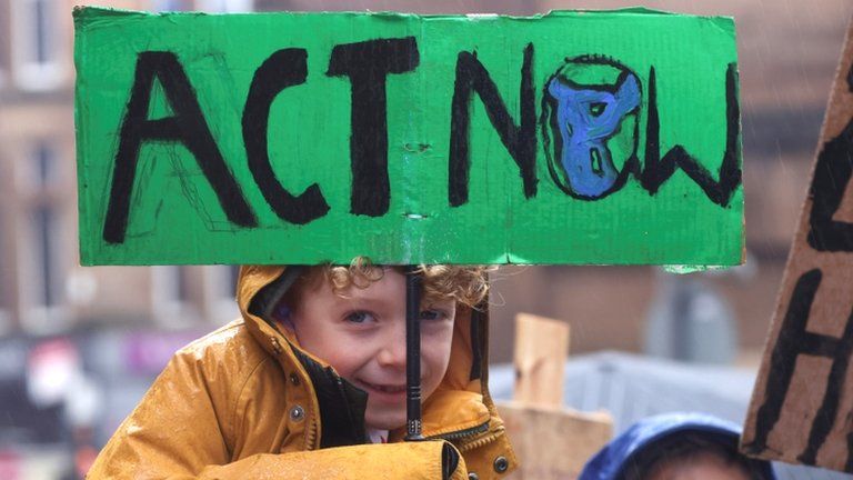 Child holding an Act Now sign