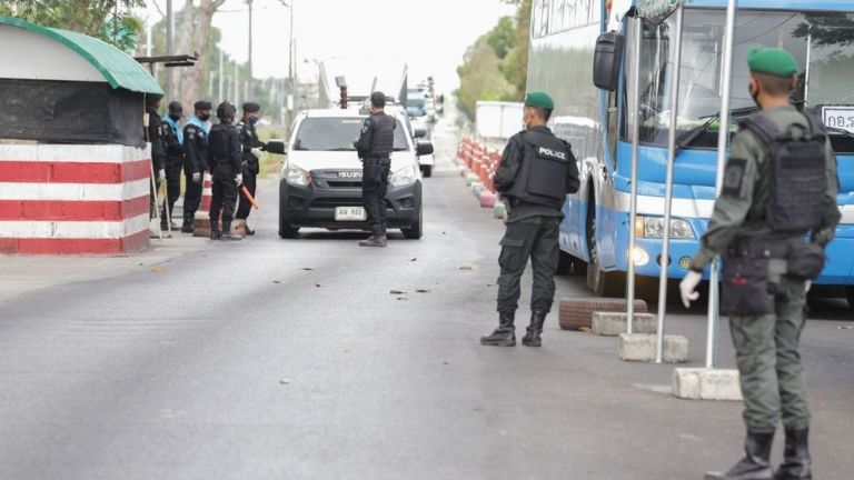 Cảnh sát và các quan chức bao quanh một chiếc xe hơi tại một trạm kiểm soát được thiết lập để ngăn chặn sự lây lan của virus corona COVID-19 ở quận Nongchik, trên biên giới của tỉnh Pattani phía nam Thái Lan vào ngày 26/3/2020