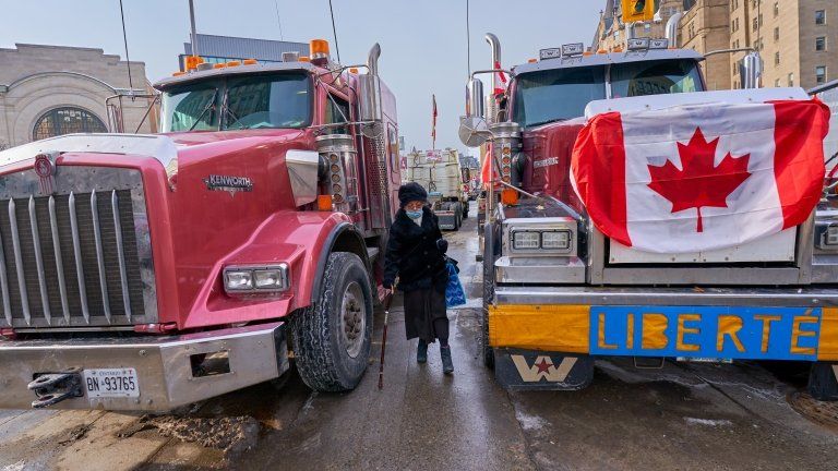 A woman walking past trucks in Ottawa