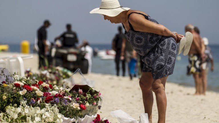 A tourist reads messages left at a makeshift memorial at the beach near the Imperial Marhaba resort