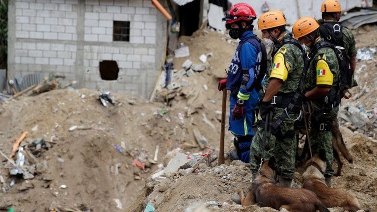 Mexican Army rescue team members and sniffer dogs survey an area affected by a mudslide in Santa Catarina Pinula on 4 October, 2015.