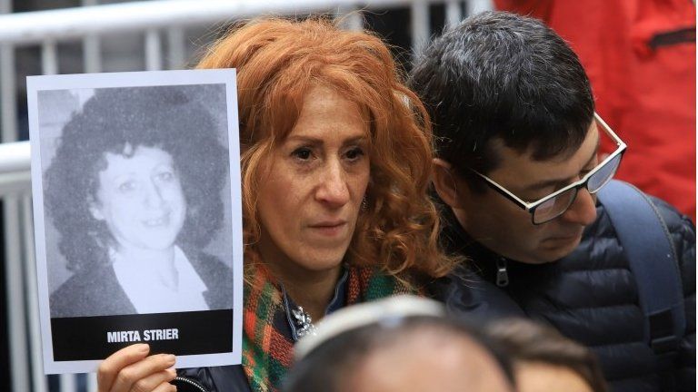Picture released by Noticias Argentinas showing a woman holding a picture of a victim of the 1994 bombing attack against the Argentine Israelite Mutual Association (AMIA) Jewish community center that killed 85 people and injured 300, during the commemoration of the attack"s 25th anniversary, in Buenos Aires on July 18, 2019.