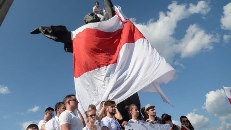 Belarusians hold up a historical flag of Belarus, during a rally in support of the opposition in Minsk, 16 Aug 2020