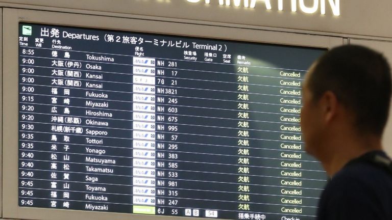 A man looks at the flight information board at the Haneda International airport in Tokyo on 12 October, 2019.