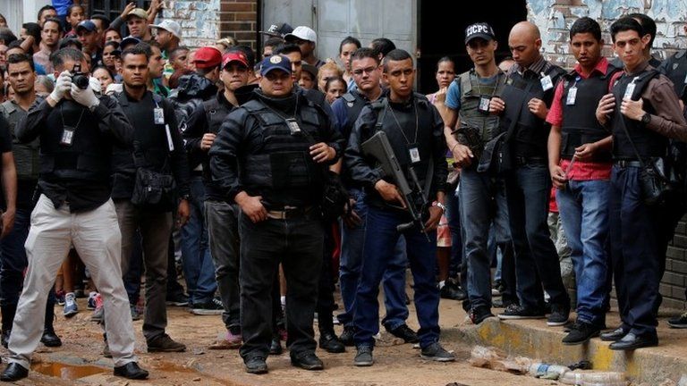Police officers and criminal investigators look for evidence in front of a bakery, after it was looted in Caracas