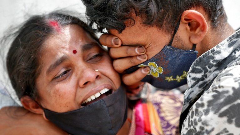 A woman mourns with her son after her husband died due to the coronavirus disease (COVID-19) outside a mortuary of a COVID-19 hospital in Ahmedabad, India, April 20, 2021.