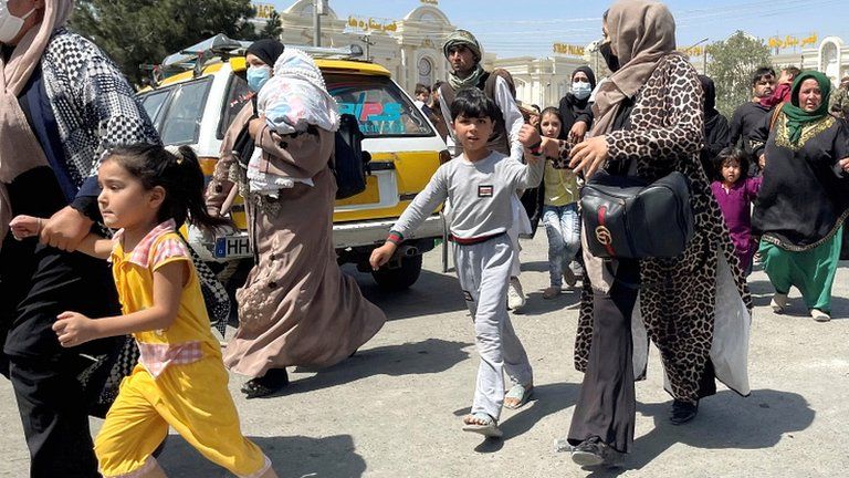 Women with their children try to get inside Hamid Karzai International Airport in Kabul on 16 August 2021