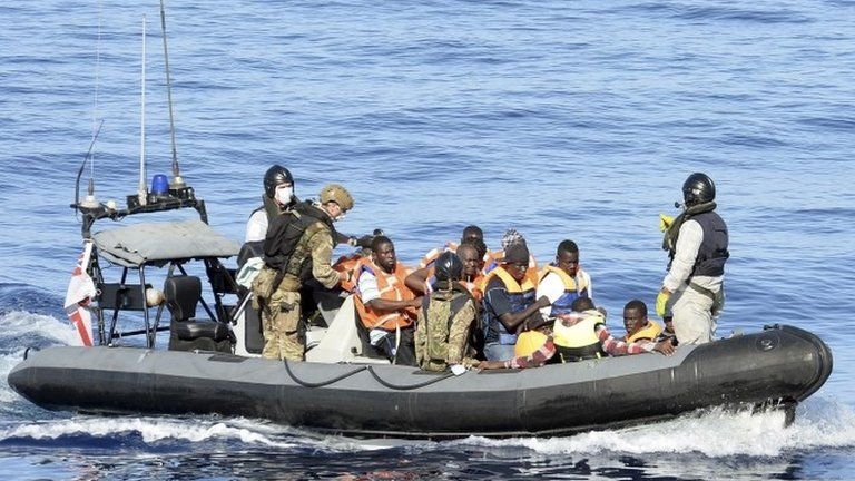 British personnel in a rigid inflatable boat assist migrants in boarding the Royal Navy ship HMS Richmond from their boat as part of the Royal Navys assistance to the EU Naval Force Operation in the Mediterranean Sea off the North Coast of Africa.
