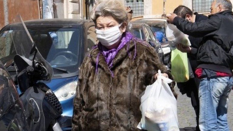 A homeless woman carries a bag with food