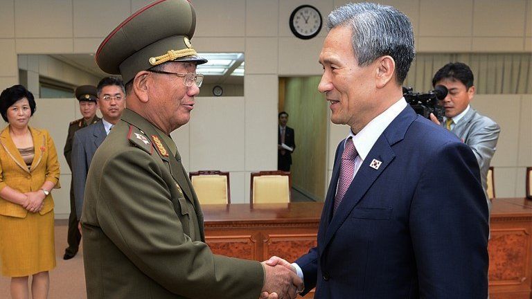South Korean presidential security adviser Kim Kwan-jin (R) shakes hands with senior North Korean official Hwang Pyong So in Panmunjom (25 Aug 2015)