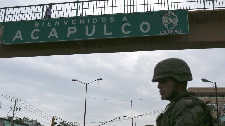 A Mexican soldier stands guard under a footbridge with an inscription that reads Welcome to Acapulco in Acapulco, Mexico on July 14, 2016.