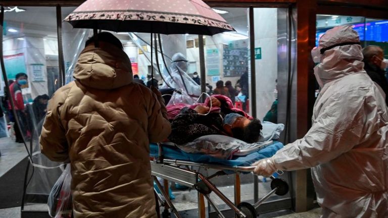 Một bệnh nhân được đưa đến bệnh viện Chữ Thập Đỏ Vũ Hán khi bên trong có hàng dài người ngồi xếp hàng chờ khám bệnh hôm 25/1