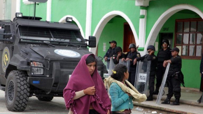 Indigenous women pass police officers standing guard in San Juan Chamula, Chiapas, Mexico, 23 July 2016