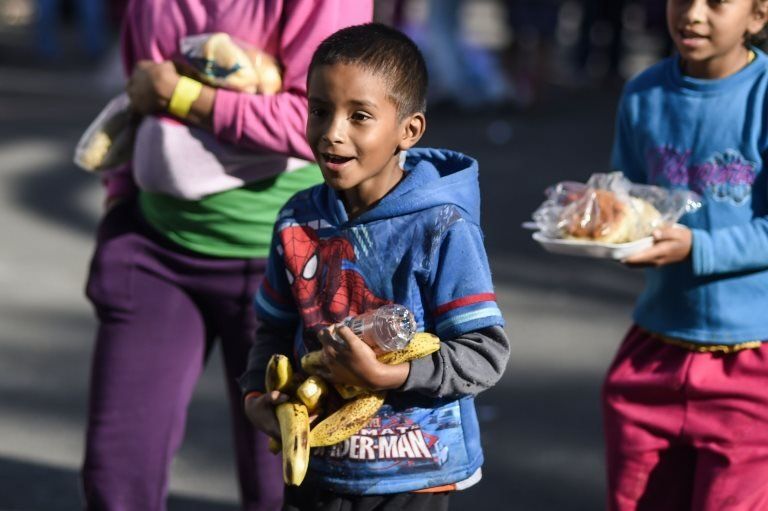 Migrant children carry bananas and other food items in the sports stadium in Mexico City where they are sheltering