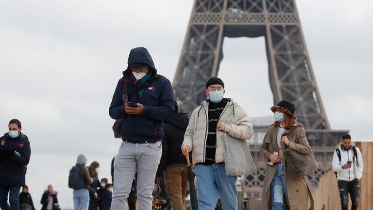 People, wearing protective face masks, walk on Trocadero square near the Eiffel Tower in Paris