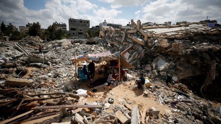 Palestinians sit in a makeshift tent amid the rubble of buildings destroyed in Israeli air strikes in Gaza (23 May 2021)