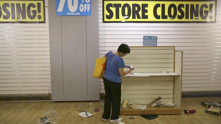 A woman looks at the last items for sale on the final day of a BHS store in London