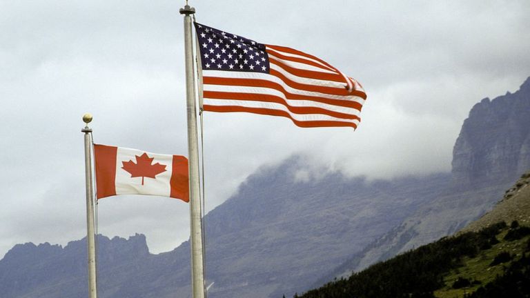 Banderas de Canadá y Estados Unidos ondean en un parque nacional de Montana