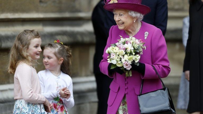 The Queen is greeted by children with flowers
