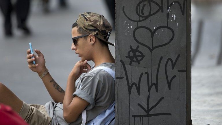 A youth checks his cell phone in Sao Paulo on 17 December, 2015.