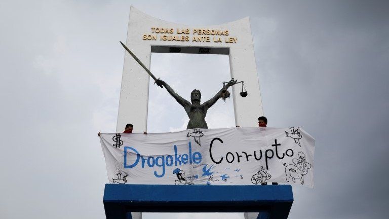 People hold a banner next to a monument, as they protest against the removal of Supreme Court judges and the Attorney General by Salvadoran congress, in San Salvador, El Salvador, May 2, 2021