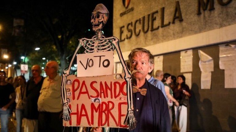 A man walks with a poster reading: "I vote while I am hungry", during the closing of the polling stations at an electoral centre in Caracas, Venezuela, 15 October 201