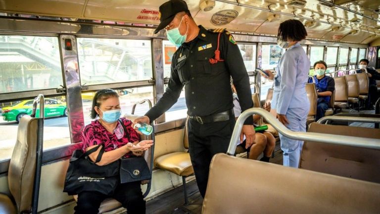 Quân đội Thái Lan phát thuốc khử trùng tay và kiểm tra nhiệt độ của hành khách trên một chuyến xe buýt đi qua một trong những trạm kiểm soát tại Bangkok