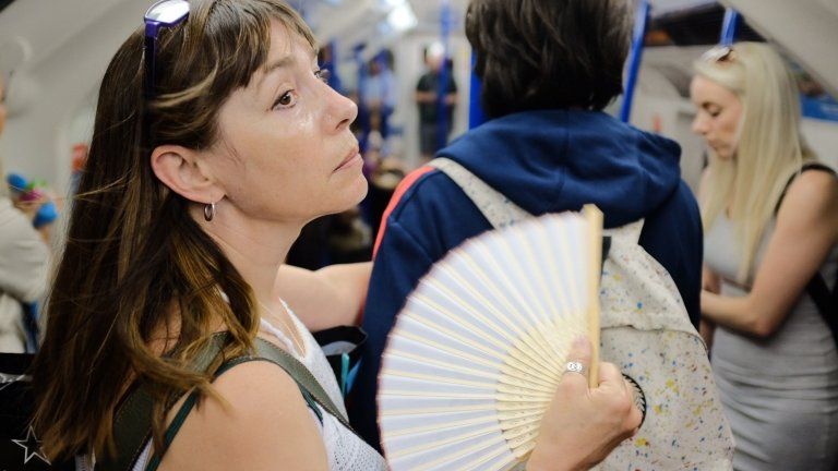 Woman with fan on tube in London