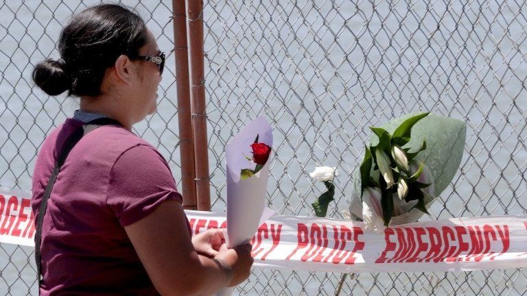 A woman places flowers in a fence in memory of victims of a volcanic eruption