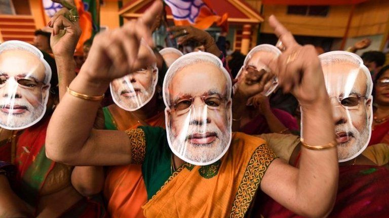 Indian Bharatiya Janata Party (BJP) supporters wearing masks of Indian Prime Minister Narendra Modi dance as they celebrate on the vote results day for India's general election at BJP office in Guwahati on May 23, 2019