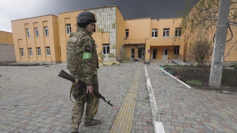 Ukrainian serviceman walks past a school damaged during a shelling in Severodonetsk,