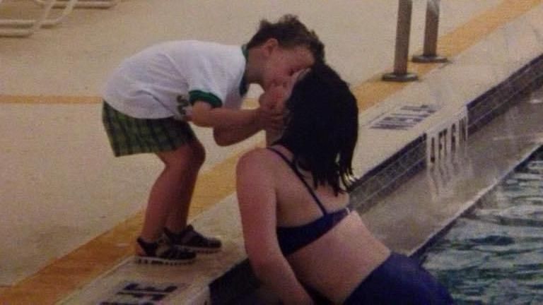 A picture of Graeme bending down to kiss his mother Joanne, who is in a swimming pool on holiday. 