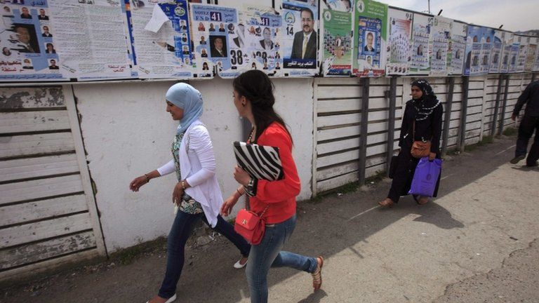 Women walk past electoral posters in Algiers May 9, 2012.
