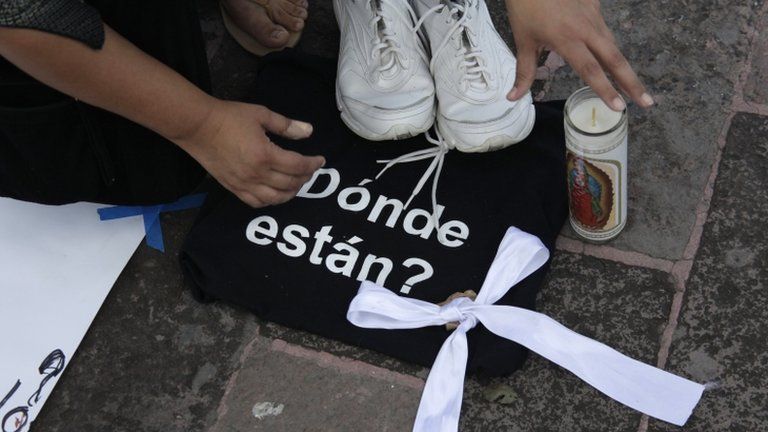 A woman places tennis shows on a black bag with the words "Where are they?" during a protest at the murder of 49 people whose bodies were found in Monterrey