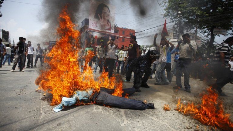 A Nepalese riot police officer drags away the burning effigy of Nepalese Prime Minister Baburam Bhattarai after it was set on fire by students affiliated to the Nepal Student Union, a student wing of the Nepali Congress Party, during a protest demanding the immediate resignation of the Prime minister in Kathmandu May 28, 2012.